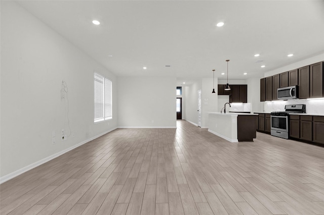 kitchen with recessed lighting, stainless steel appliances, open floor plan, and light wood-style flooring