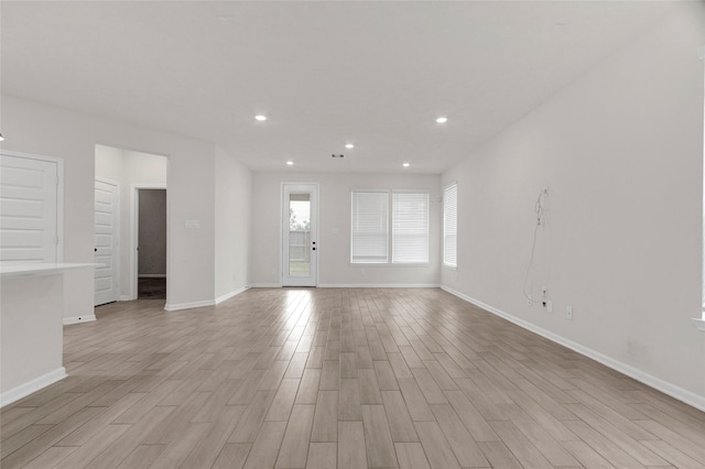 unfurnished living room with recessed lighting, baseboards, and light wood finished floors