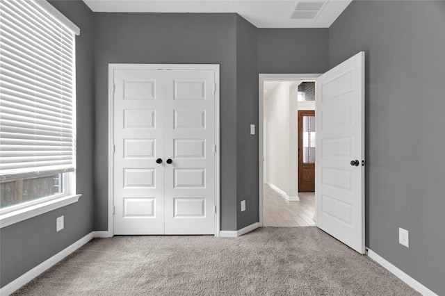 unfurnished bedroom with a closet, visible vents, baseboards, and carpet floors