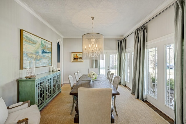 dining room featuring a healthy amount of sunlight, crown molding, a textured ceiling, and an inviting chandelier