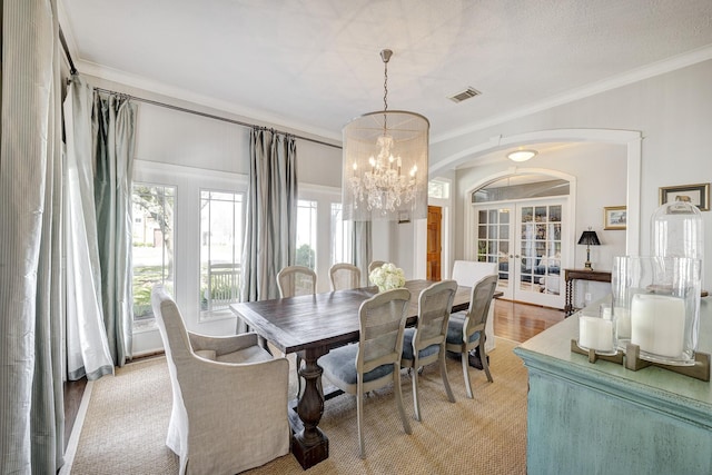 dining space featuring arched walkways, french doors, visible vents, an inviting chandelier, and ornamental molding