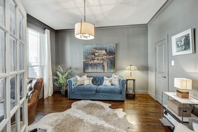 living area featuring crown molding, baseboards, and wood finished floors