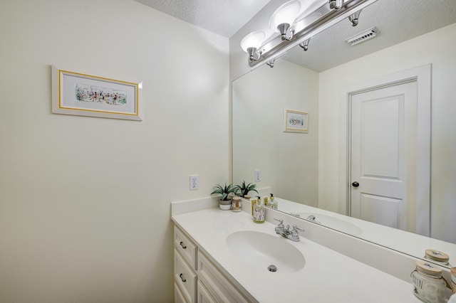 bathroom featuring a textured ceiling, vanity, and visible vents