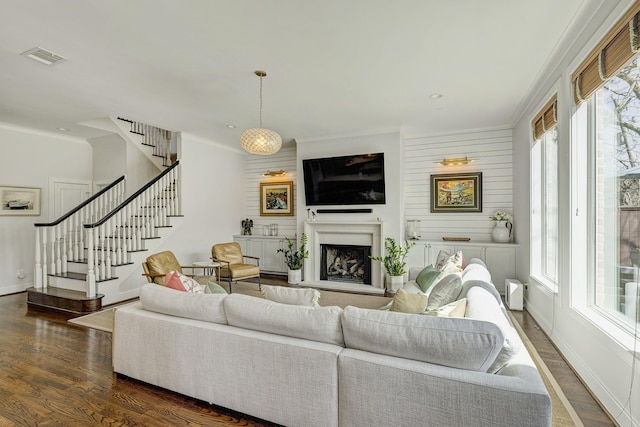 living room with baseboards, visible vents, a fireplace with raised hearth, stairway, and dark wood-type flooring