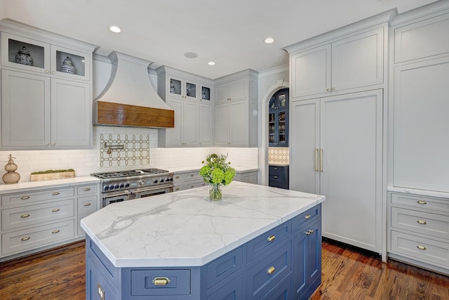 kitchen with premium appliances, blue cabinets, custom exhaust hood, a center island, and dark wood-style floors