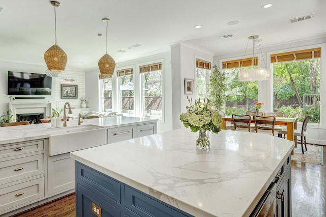 kitchen with ornamental molding, a center island, visible vents, and a sink