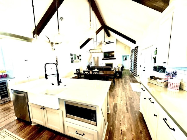 kitchen featuring dark wood-style floors, stainless steel appliances, a fireplace, and beam ceiling