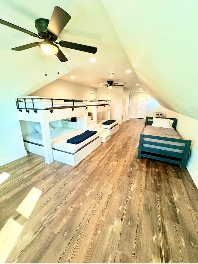 interior space with baseboards, visible vents, wood finished floors, vaulted ceiling, and recessed lighting