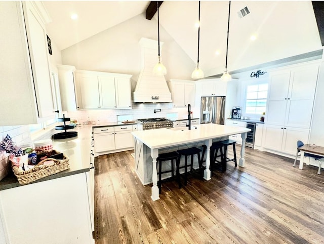 kitchen with stainless steel fridge with ice dispenser, stove, beamed ceiling, wood finished floors, and backsplash