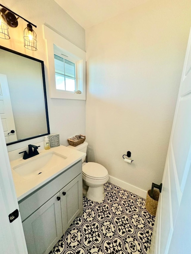 bathroom featuring toilet, tile patterned flooring, vanity, and baseboards