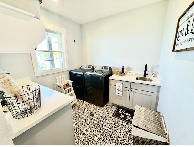 clothes washing area with cabinet space, light tile patterned floors, washer and clothes dryer, and a sink