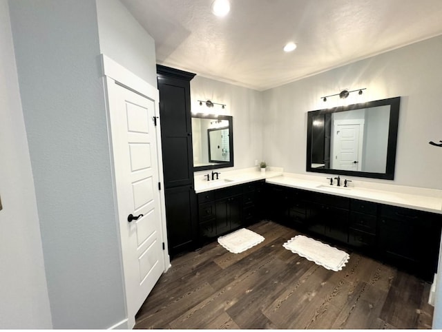 bathroom featuring recessed lighting, double vanity, a sink, and wood finished floors