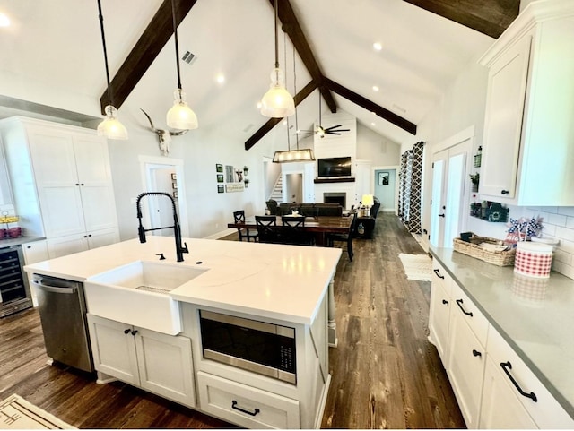 kitchen with beam ceiling, a fireplace, stainless steel appliances, dark wood-type flooring, and a sink