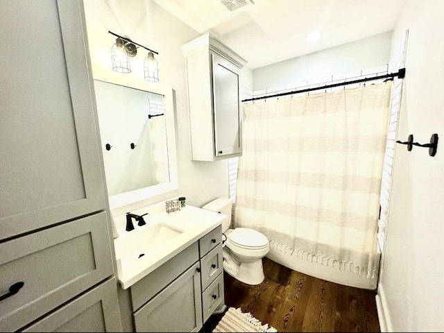 bathroom featuring visible vents, toilet, shower / bath combo with shower curtain, vanity, and wood finished floors