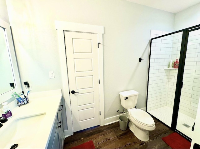 full bathroom featuring toilet, wood finished floors, vanity, baseboards, and a stall shower