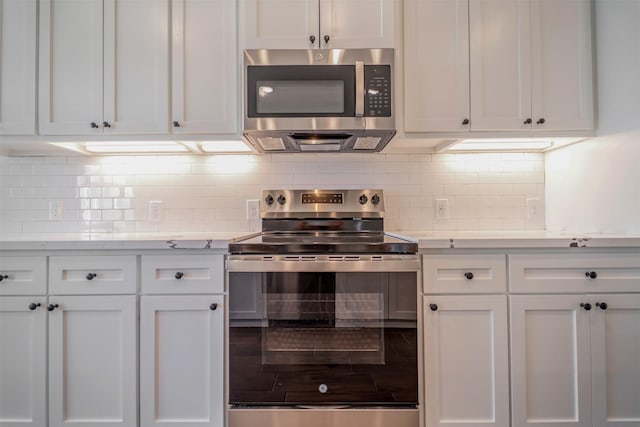 kitchen with light stone countertops, white cabinetry, appliances with stainless steel finishes, and decorative backsplash