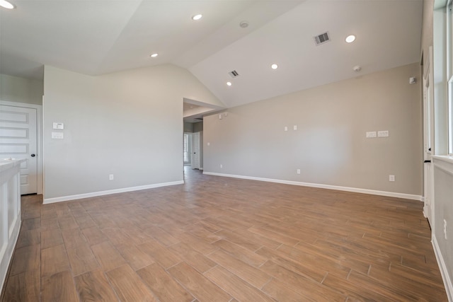 empty room featuring vaulted ceiling, light wood finished floors, and baseboards