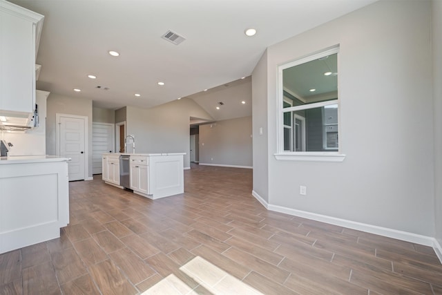 interior space with visible vents, dishwasher, open floor plan, light countertops, and white cabinetry