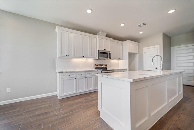 kitchen featuring stainless steel appliances, tasteful backsplash, visible vents, white cabinetry, and a sink