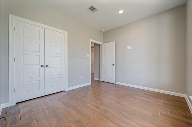 unfurnished bedroom with baseboards, visible vents, light wood-type flooring, a closet, and recessed lighting