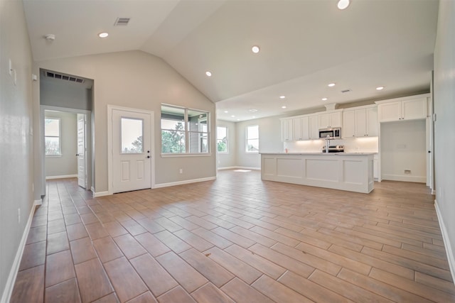 unfurnished living room with lofted ceiling, visible vents, light wood finished floors, and recessed lighting