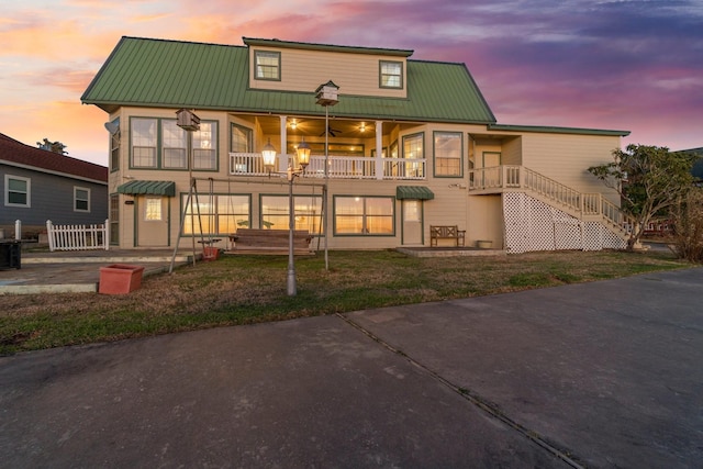 view of front of property featuring a balcony, stairway, metal roof, and a patio