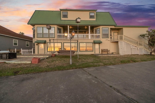 back of property at dusk featuring a balcony, a patio area, and metal roof