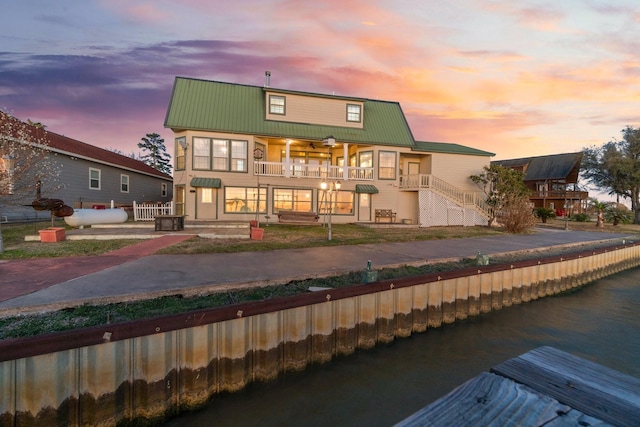 back of property at dusk with metal roof and a water view