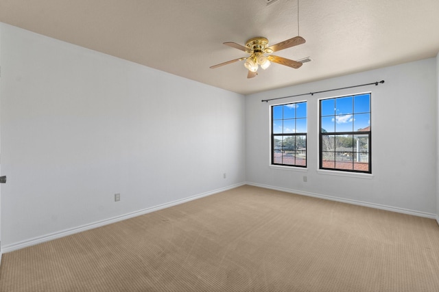 spare room featuring baseboards, ceiling fan, visible vents, and light colored carpet