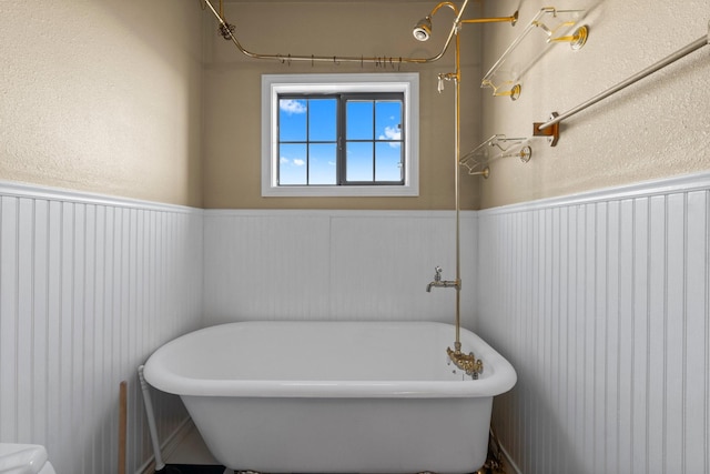 bathroom with a freestanding tub and a wainscoted wall