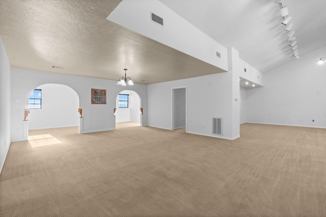 unfurnished living room with visible vents, arched walkways, and light colored carpet