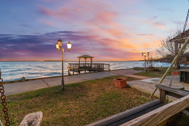 dock area featuring a water view, a gazebo, and a yard