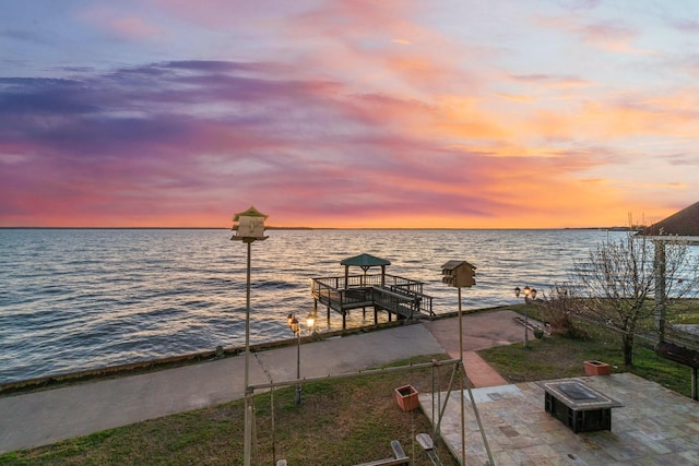 dock area with an outdoor fire pit, a water view, and a patio