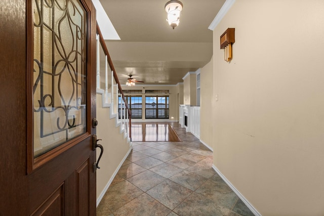 foyer featuring baseboards, a ceiling fan, and crown molding