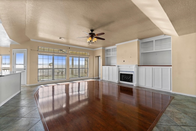 unfurnished living room with ceiling fan, a textured ceiling, plenty of natural light, and a fireplace