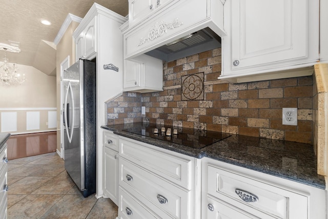 kitchen featuring white cabinets, custom range hood, black electric stovetop, and stainless steel refrigerator with ice dispenser