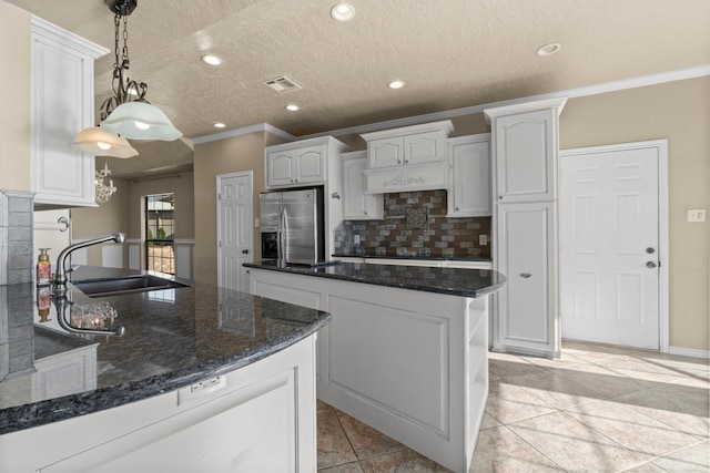 kitchen with visible vents, stainless steel fridge with ice dispenser, a center island, a sink, and backsplash