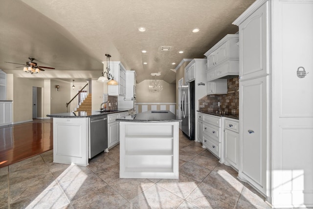 kitchen featuring dark countertops, a peninsula, stainless steel appliances, and decorative backsplash