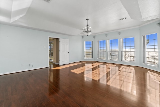 empty room with baseboards, visible vents, wood finished floors, a textured ceiling, and a chandelier