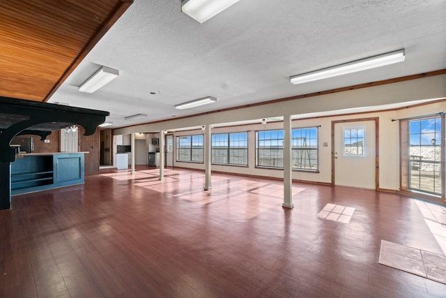 interior space featuring a textured ceiling, arched walkways, and wood finished floors