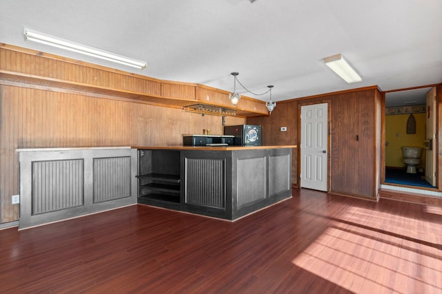 kitchen with hanging light fixtures, wood walls, wood finished floors, and freestanding refrigerator