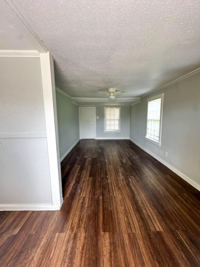 empty room with dark wood-style floors, crown molding, baseboards, and a ceiling fan