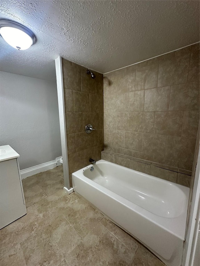 bathroom with baseboards, vanity, a textured ceiling, and bathing tub / shower combination