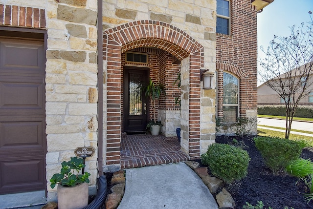 property entrance featuring a garage, stone siding, and brick siding