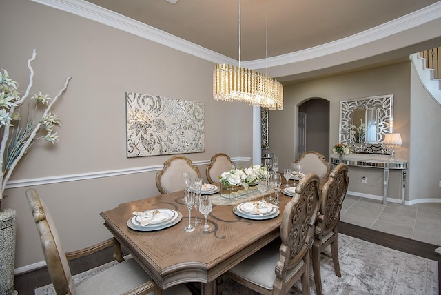 dining space featuring wood finished floors, baseboards, ornamental molding, stairway, and an inviting chandelier