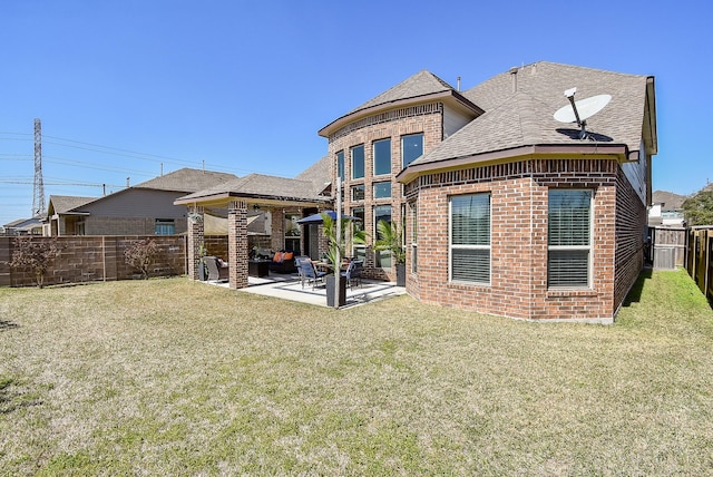 rear view of house with a patio, a fenced backyard, brick siding, a yard, and roof with shingles