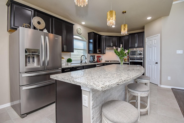 kitchen featuring stainless steel appliances, a sink, decorative backsplash, and light stone counters