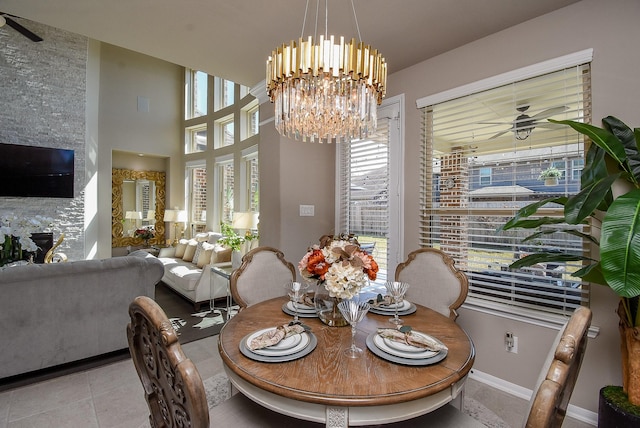 dining space featuring tile patterned flooring, baseboards, and ceiling fan with notable chandelier