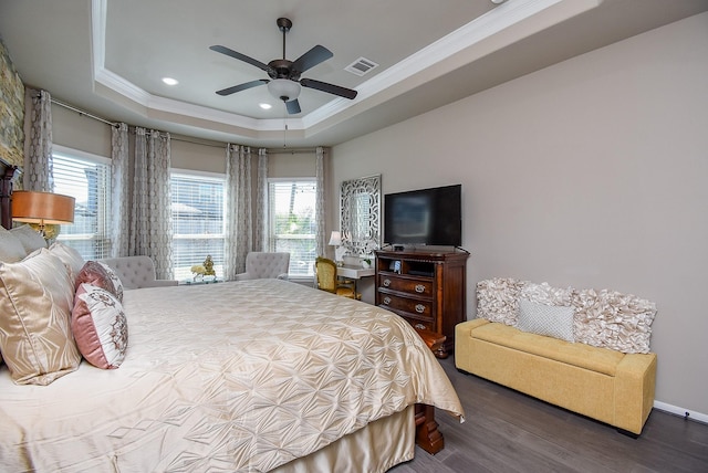 bedroom with visible vents, a raised ceiling, ceiling fan, wood finished floors, and crown molding