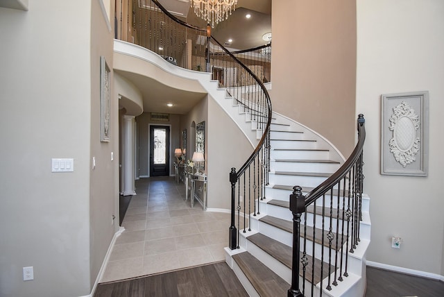 entryway with visible vents, wood finished floors, a towering ceiling, and baseboards